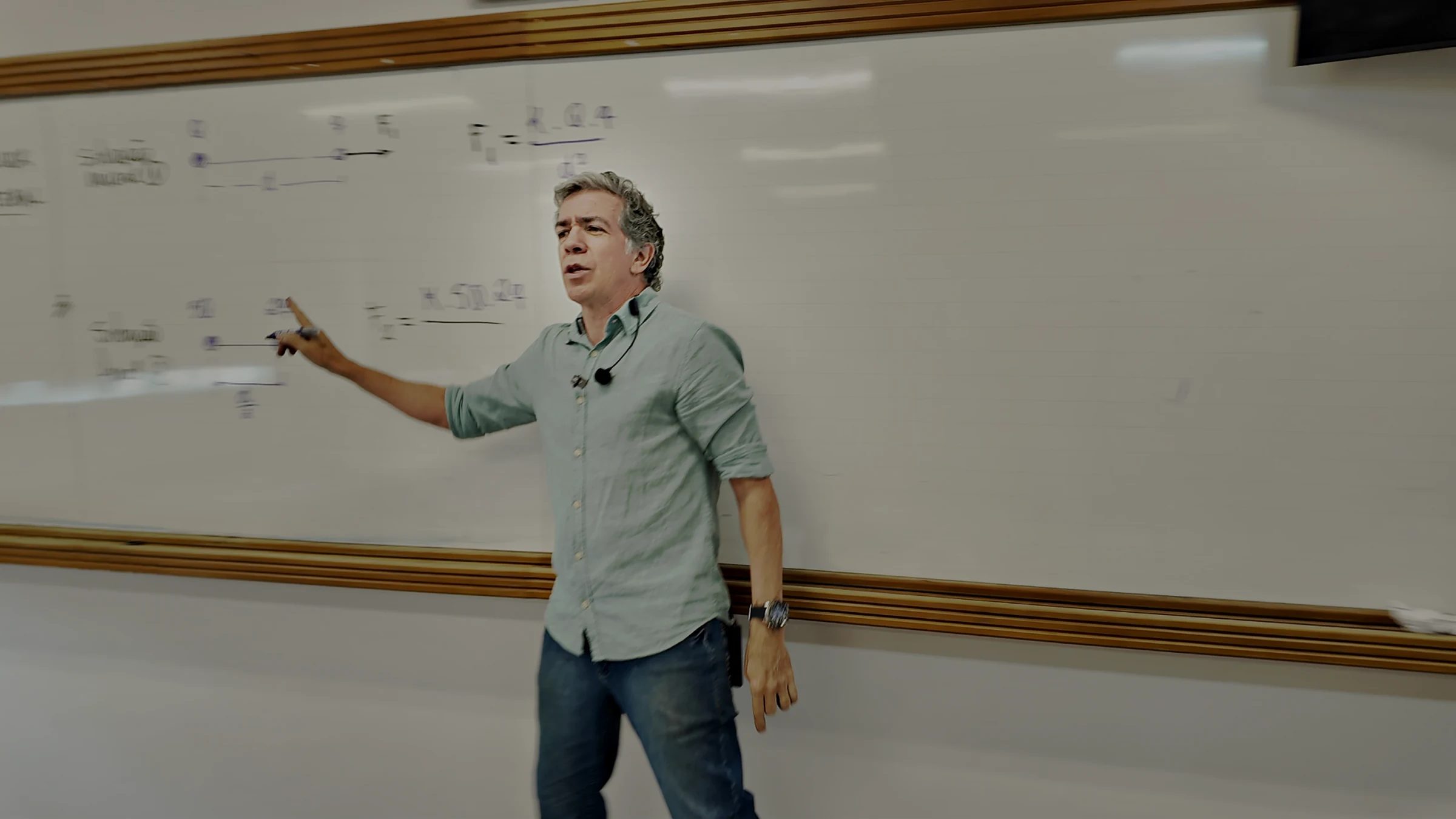 Professor Pinguim apontando para a conta escrita no quadro branco, durante uma aula presencial
