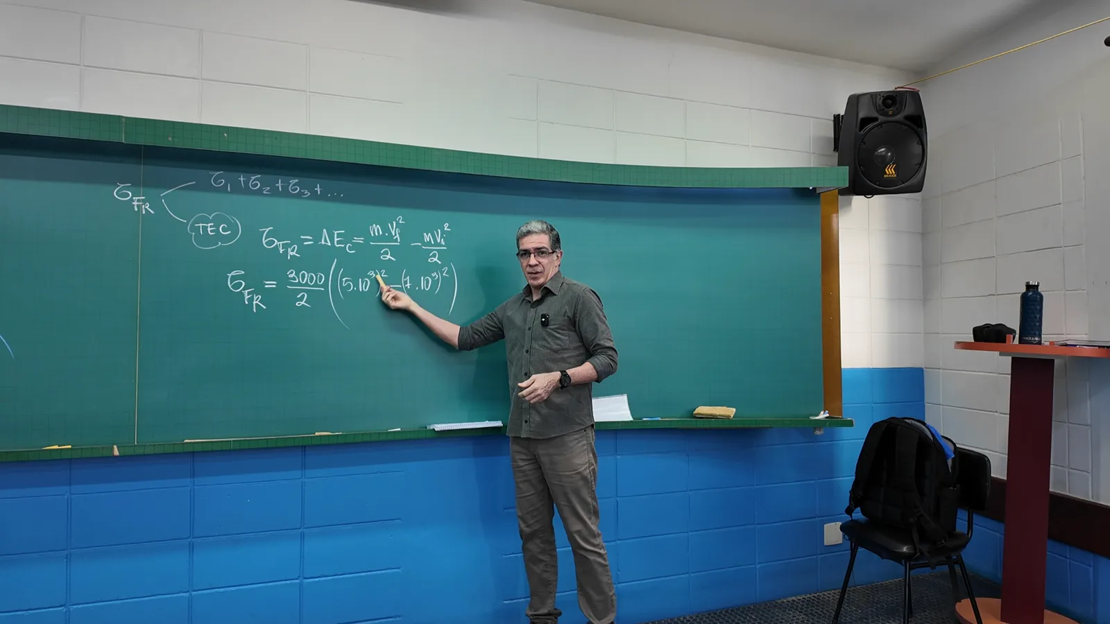 Professor Pinguim apontando para o Teorema da Energia Cinética escrito no quadro verde da sala